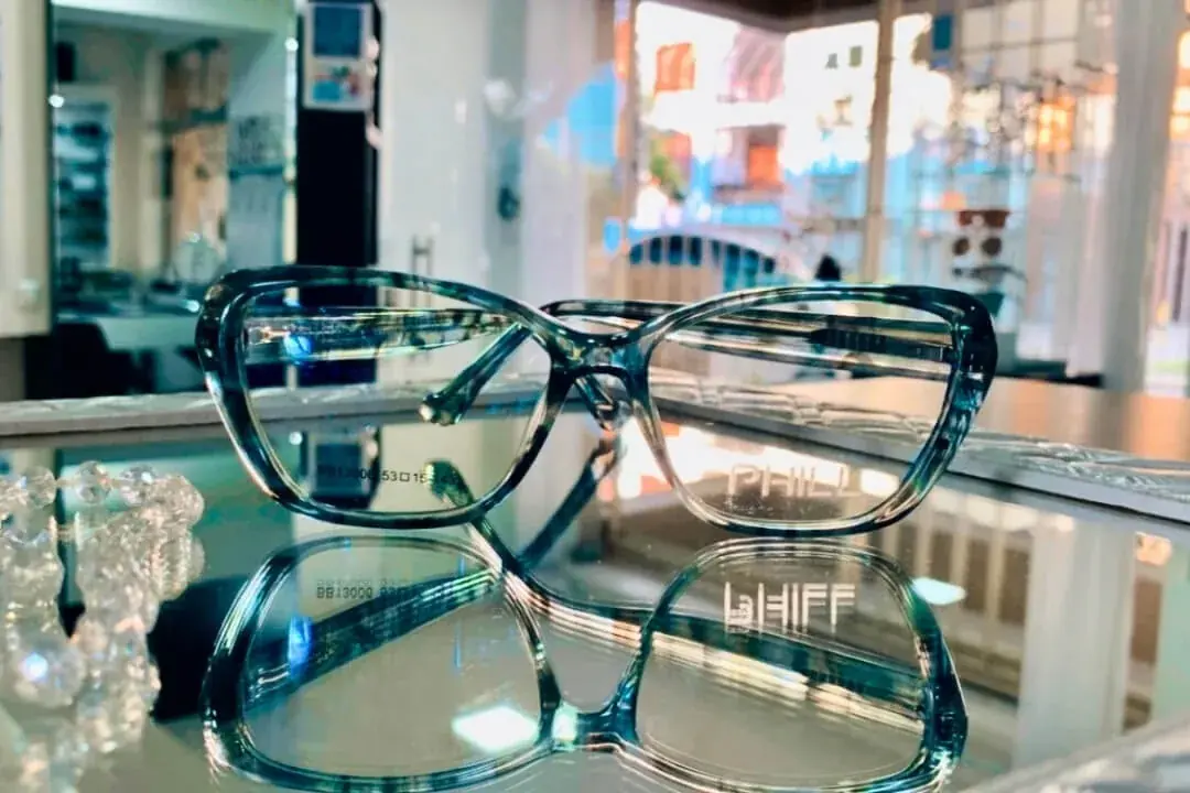 Armação de óculos de grau em acetato azul translúcido sobre a vitrine da Óptica Visualisi, Porto Alegre