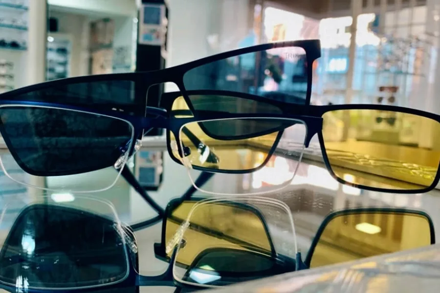 Armações de óculos com lentes de tonalidade amarela e azul sobre a vitrine da Óptica Visualisi, Porto Alegre