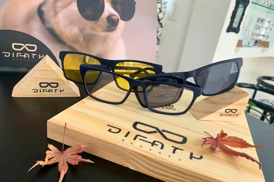 Óculos com clip-on solar e lente amarela para direção noturna expostos na Óptica Visualisi, Porto Alegre